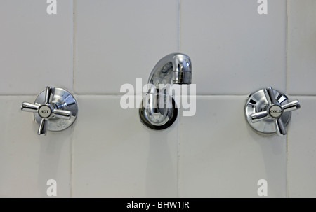 Robinets dans une salle de bains affichant des étiquettes chaud et froid Banque D'Images