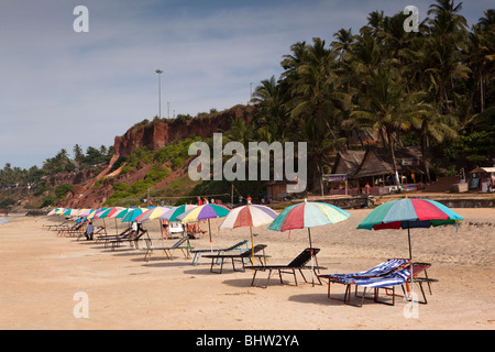 L'Inde, le Kerala, Varkala plage, parasols colorés et transats vides au-dessous des falaises Banque D'Images