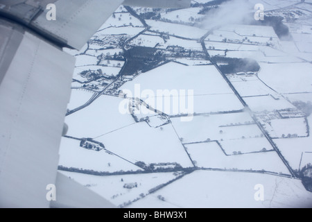 Regardant par la fenêtre d'un avion survolant les champs couverts de neige dans le Royaume-Uni l'angleterre Banque D'Images