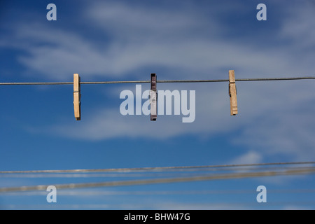 Trois des pinces à linge suspendu à un contre un ciel bleu Banque D'Images