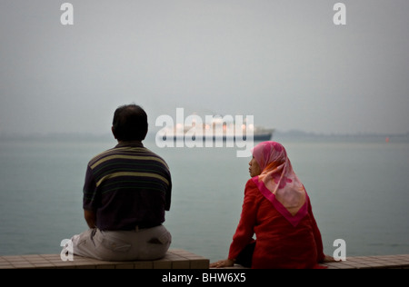 Couple musulman s'asseoir et regarder l'eau de mer à Georgetown, Penang Palau Banque D'Images
