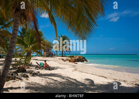 Pigeon Point Park Beach Tobago avec mer des Caraïbes côte bordée de palmiers lifeguard assis point revêtus femme bikini Banque D'Images