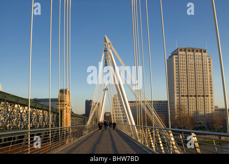 Les gens qui marchent le long de la Golden Jubilee Bridge dans le centre de Londres avec le Shell building en arrière-plan. Banque D'Images