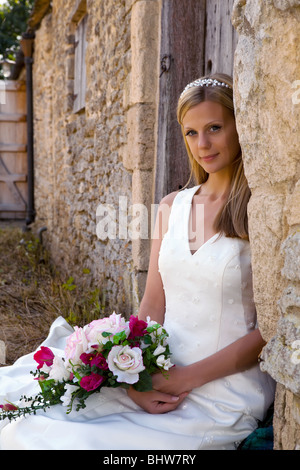 Jeune blonde bride en blanc contre un mur de la grange médiévale grunge Banque D'Images