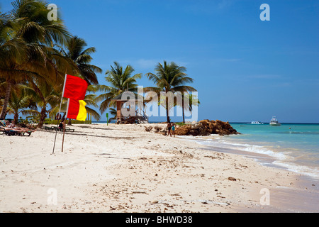 La plage de Pigeon Point Tobago avec ciel bleu soleil tropical en rouge et jaune sur l'affichage des drapeaux de sauveteur. Banque D'Images