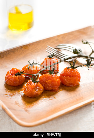 Tomates cerises rôties sur une portion plater avec de l'huile d'olive en arrière-plan Banque D'Images