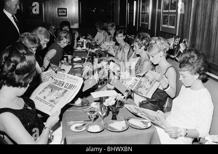 1966 Tournoi de Coupe du Monde en Angleterre. Un banquet a eu lieu la coupe du monde pour l'équipe de l'Angleterre victorieuse au Royal Garden Hotel après leur victoire sur l'Allemagne de l'Ouest en finale à Wembley. Épouses des joueurs qui ont dû manger un dîner séparé de leur mari, y compris Mme Tina Moore, Mme Peters, Mme Hurst, Mme Springett et Mme Bonetti lire le journal Sunday Mirror. Le 31 juillet 1966. Banque D'Images