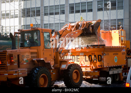 NYC Department de l'assainissement des travailleurs utilisent un chargeur avant de déposer des montagnes de neige dans un fondeuse à neige dans le Lower Manhattan à New York Banque D'Images