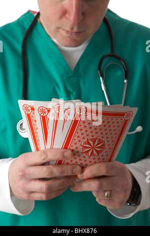 Man wearing scrubs medical stéthoscope et la tenue d'une série de cartes à jouer Banque D'Images