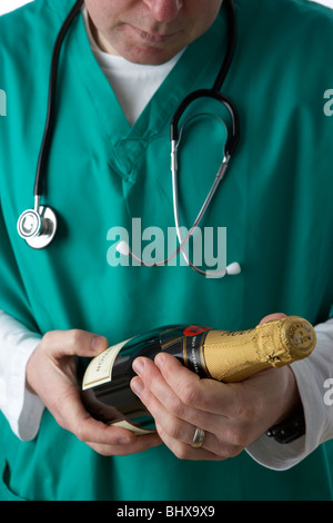 Man wearing scrubs medical holding stethoscope et bouteille de champagne Banque D'Images