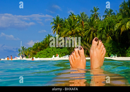 Womens pieds , Palmiers à la plage de Biyadhoo Island , Océan Indien , South Male Atoll, Maldives Banque D'Images