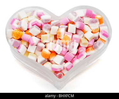 Mélange Dolly bonbons dans un plat en verre en forme de coeur isolé comme une découpe contre un fond studio blanc Banque D'Images