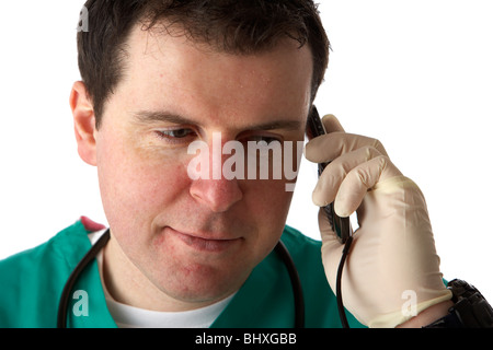 Man wearing scrubs medical stéthoscope et holding mobile phone à son oreille en souriant Banque D'Images