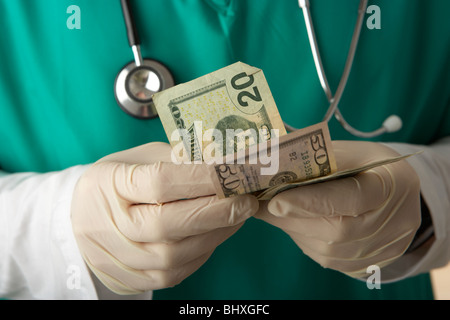 Man wearing scrubs medical stéthoscope et compter les billets en dollars us Banque D'Images