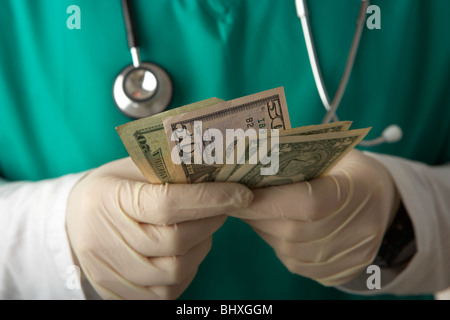 Man wearing scrubs medical stéthoscope et compter les billets en dollars us Banque D'Images