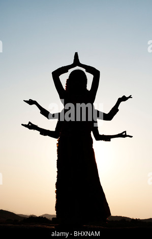 Silhouette de trois filles indiennes dans un six classique déesse hindoue armés posent au coucher du soleil. L'Inde Banque D'Images