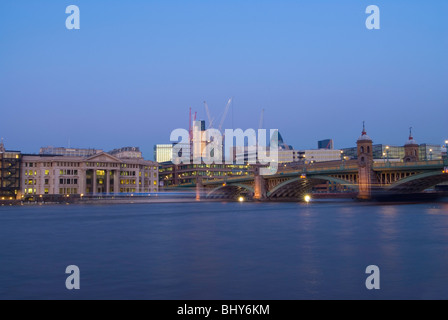 Southwark Bridge dans le centre de Londres à la recherche de la Banque du Sud en début de soirée avec un bateau voyageant passé laissant light trails Banque D'Images