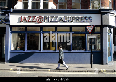 Homme marchant passé la boutique à l'avant @ Jazz Pizza Express restaurant à Dean Street, Soho, London, UK. Nov 2009 Banque D'Images