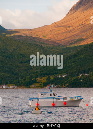 Terre-neuve, l'homme vers l'aviron bateau de pêche en Baie de Bonnie. Le parc national du Gros-Morne et Tablelands les montagnes. Banque D'Images