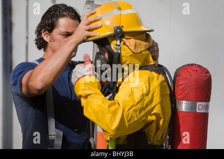 Un pompier est aidé d'avoir mis sur son équipement avant de s'attaquer à un incident aux matières dangereuses Banque D'Images