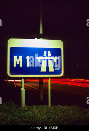 Des sentiers des projecteurs le trafic passant roadsign affirmant début de l'autoroute M1 au crépuscule près de Leeds Yorkshire UK Banque D'Images