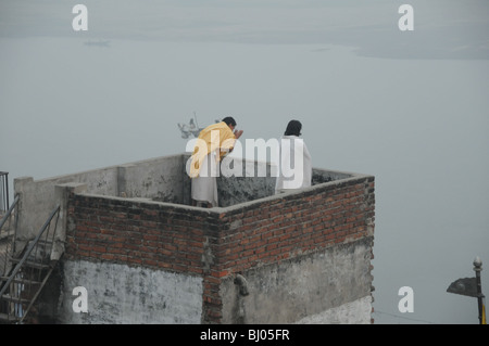 Deux hommes debout sur le toit en parlant de l'esprit du smog varanasi Banque D'Images