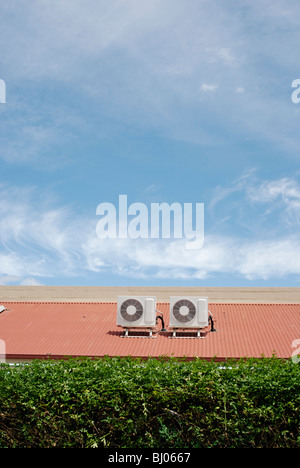 Climatiseurs de toit entre une haie verte et bleu ciel. Banque D'Images