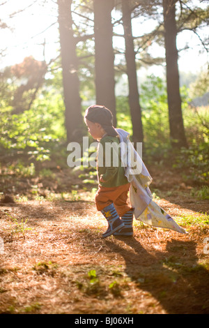 Jeune garçon portant une couverture dans les bois. Banque D'Images