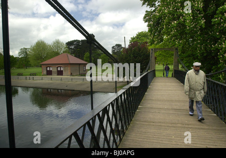 Homme âgé marche à travers un pont en Wardown Park Luton, Bedfordshire, Royaume-Uni Banque D'Images