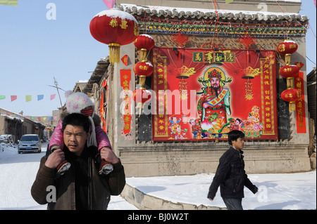 Les villageois passé une peinture du dieu de la richesse sur un mur pendant la fête du printemps dans la province de Hebei, Chine. 01-Mar-2010 Banque D'Images