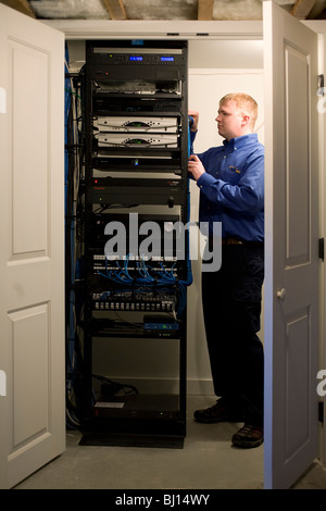 Technicien en électronique qui installe l'exploitation et d'élaborer un système de divertissement à domicile. Les composants sont cachés dans le sous-sol. Banque D'Images