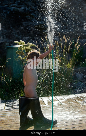 Un petit garçon debout dans de grandes bottes de caoutchouc d'eau l'eau, la Suède. Banque D'Images