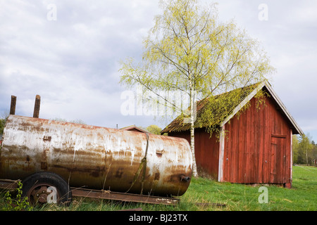 Ancien réservoir rouillé et les jeunes arbres de bouleau au printemps. Banque D'Images