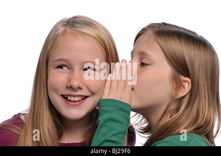 Les petites filles partageant un secret isolé sur fond blanc Banque D'Images