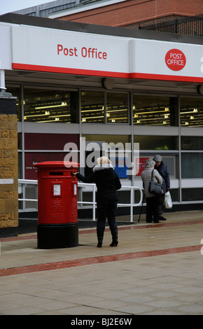 Bureau de poste et un couple de personnes âgées ayant un chat à l'extérieur de cette branche à Solihull Birmingham Les Midlands England UK Banque D'Images