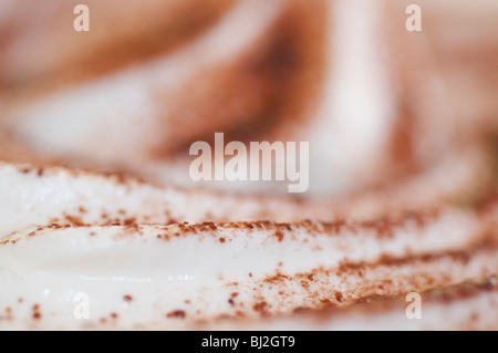 Tourbillon de la crème ou du lait sur le dessus d'une tasse de café ou de chocolat chaud recouvert de chocolat en poudre Banque D'Images