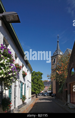 Clocher de l'église et maisons blanches décorées de fleurs dans le vieux centre d'Oud-Rekem, Maasland, Belgique Banque D'Images