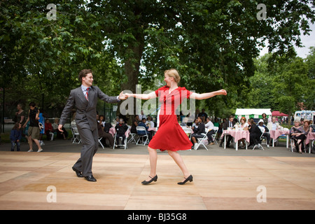 Un jeune couple démontrent leur rock 'n' roll compétences danse devant une foule en champs Myatts park dans Camberwell. Banque D'Images