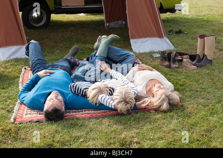 Famille couchée en face de la tente Banque D'Images