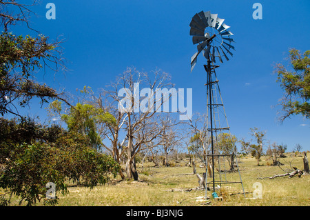 NOUVELLE-GALLES DU SUD RURALE, Australie — Un moulin à vent solitaire se dresse contre le vaste paysage ouvert d'une ferme dans la Nouvelle-Galles du Sud rurale. La structure emblématique, silhouette sur le ciel, sert de source d'eau vitale dans ce vaste cadre agricole. Banque D'Images