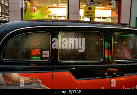 Un London taxi cab est humide mais après de fortes pluies en stationnement dans une rue latérale au large de Charing Cross Road. Banque D'Images