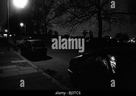 Tard dans la nuit dans une rue du sud de Londres, deux jeunes enfants sont encore endormi à l'arrière de leur voiture des parents. Banque D'Images