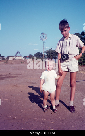 Un jeune homme de 10 pose pour un portrait pris par son frère tout en tenant la main de son jeune neveu. Banque D'Images