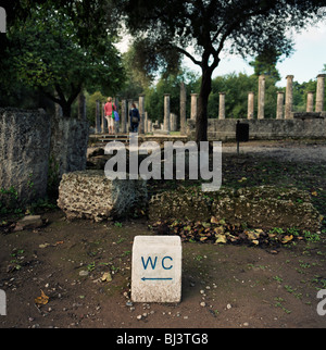 Un signe se trouve près de la toilette des colonnes doriques permanent et les touristes à l'ancienne Olympie Palestre ou wrestling school. Banque D'Images