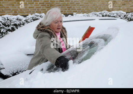 Woman cleaning la fenêtre d'une voiture de la neige Banque D'Images