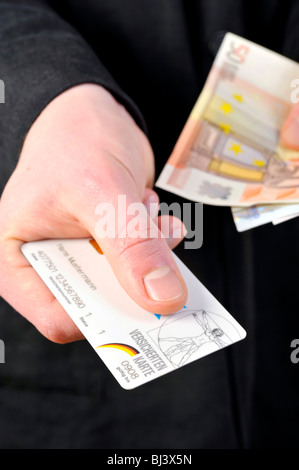 La main avec la carte d'assurance et de l'introduction des billets Banque D'Images