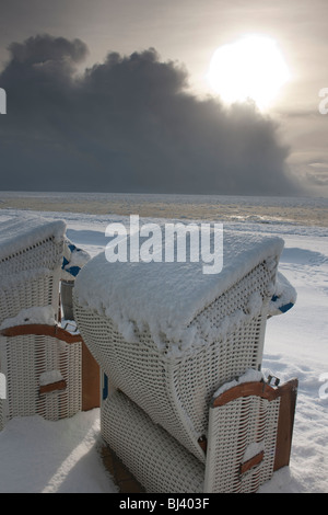 Des chaises de plage en osier avec vue sur un paysage de neige et de glace sur la plage sud de Wyk de la mer du Nord île de Foeh Banque D'Images