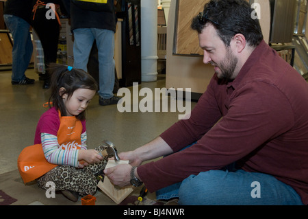 Trois ans, avec l'aide de son père, s'appuie un pluviomètre à un atelier pour les enfants à New York Banque D'Images