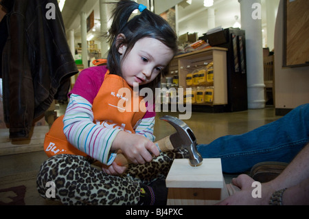 Trois ans, avec l'aide de son père, s'appuie un pluviomètre à un atelier pour les enfants à New York Banque D'Images