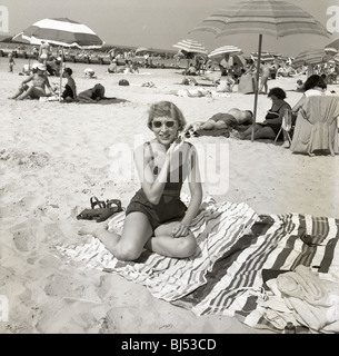 Mode femme à la plage durant les années 1950. smiling happy fashion soleil sable parasols Banque D'Images